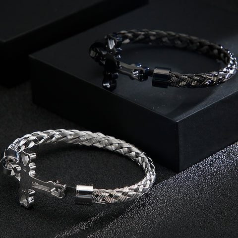 Bracelete prata e bracelete preto em fundo escuro.
