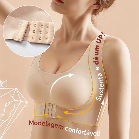 Modelo usando sutiã na cor nude e detalhe dos fechos. Texto: Sustenta e dá um UP! Modelagem confortável.